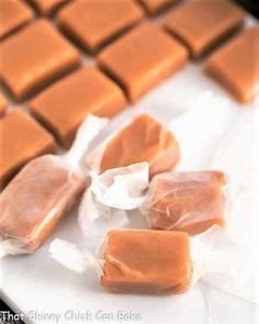 pieces of caramel candy sitting on top of a white plate with plastic wrappers