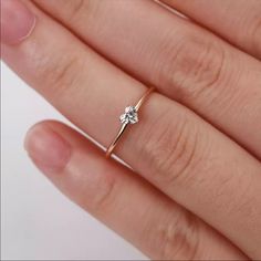 a woman's hand with a diamond ring on top of her finger, against a white background