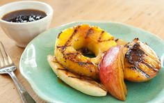 two pieces of fruit are on a plate next to a fork and cup of coffee