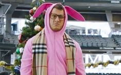 a man in a pink bunny costume standing next to a christmas tree