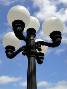 a street light with three white lamps on it's side and blue sky in the background