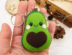 a hand holding a keychain shaped like a cucumber with a heart on it