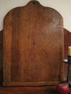 an old wooden cutting board sitting on top of a table next to an apple and knife