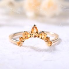 a gold ring with three orange stones on it's sides, sitting on a white surface