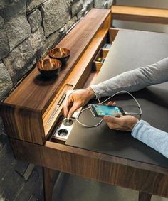 a person using their cell phone at a table with an ipod and charger plugged in