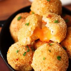 some fried food in a black bowl on a wooden table with parsley sprinkled around it