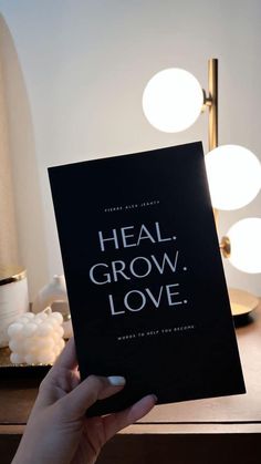 a person holding up a book with the words heal, grow, love on it