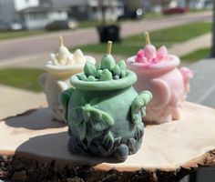 three different colored candles sitting on top of a piece of wood next to each other