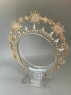 a gold tiara with crystal stars on it's head and clear acrylic stand