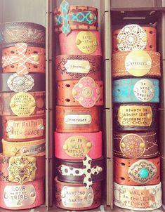 several different types of leather bracelets in a display case with tags and charms on them