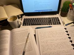 an open laptop computer sitting on top of a desk next to notebooks and coffee