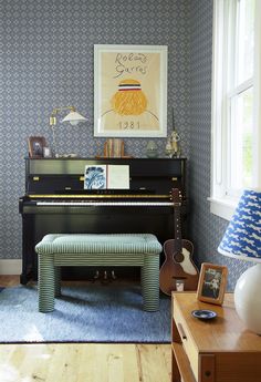 a living room with a piano in the corner and blue wallpaper on the walls