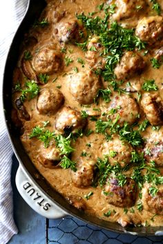 meatballs and gravy in a pan with parsley on the side, ready to be eaten