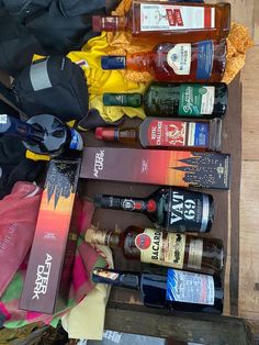 an assortment of alcohol bottles are lined up on a wooden table next to other items