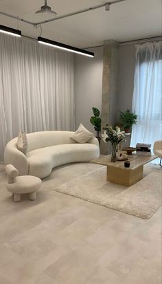 a living room with white furniture and curtains