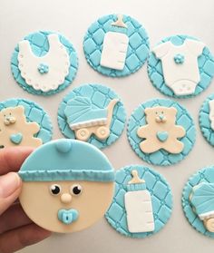 baby shower cookies with blue icing and white frosting are being held by a person's hand