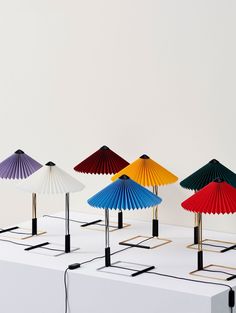 four different colored umbrellas sitting on top of a white table next to each other