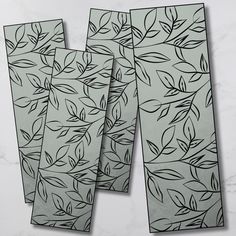 three placemats with leaves on them sitting on a marble counter top next to each other