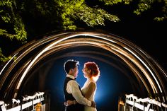 a bride and groom standing on a bridge at night