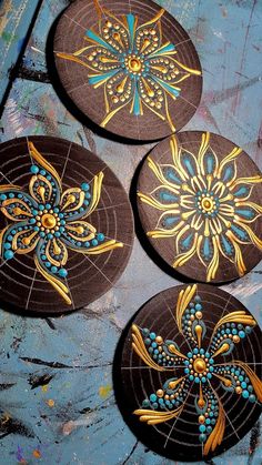 three circular wooden coasters with designs painted on them sitting on a blue table top