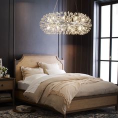 a bedroom with a large bed and chandelier hanging from the ceiling above it