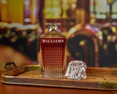 a bottle of william's whiskey sitting on top of a wooden tray next to a diamond