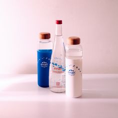 three bottled water bottles sitting on top of a white table next to each other,