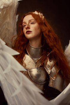 a woman with red hair and armor is posing for a photo in white paper wings