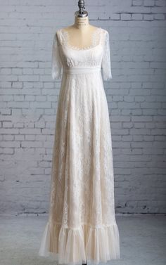 a white dress on a mannequin stand in front of a brick wall,