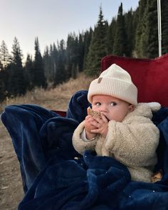 a baby sitting on a blanket eating something