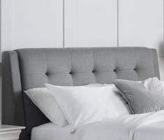 a bed with white pillows and gray headboard