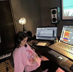 a woman sitting in front of a laptop computer on top of a desk next to sound mixing equipment