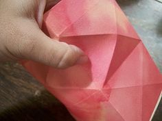 a hand holding a piece of pink paper