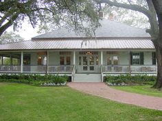 a white house with porches and trees in the front yard