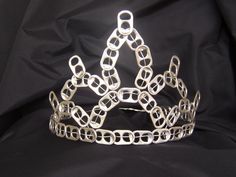 a tiara made out of metal links on a black cloth covered background with space for text