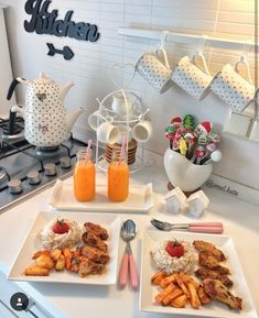 two white plates topped with food on top of a counter next to cups and utensils