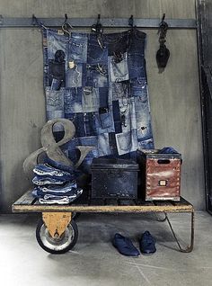 a table topped with lots of different types of clothing next to a wall hanging on hooks