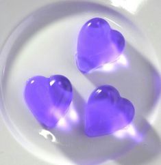 three purple heart shaped candies on a white plate