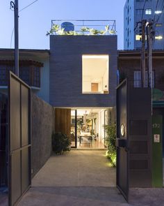 an entrance to a house with plants growing on the roof and in between two buildings