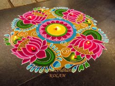 a colorful flower design is on the ground with candles in it and some lights are lit