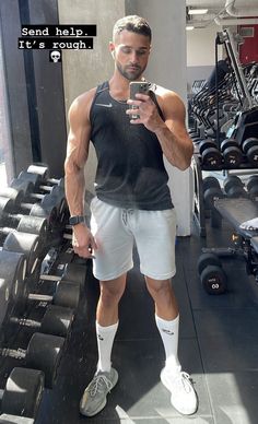 a man taking a selfie in the gym with his cell phone and dumbbells