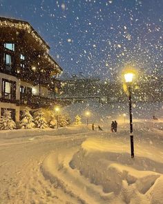 a snow covered street light in front of a building