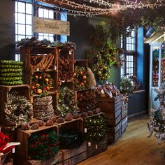 christmas decorations are on display in a store with wooden crates filled with pine cones, oranges and other holiday items