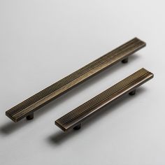 two brass drawer pulls on a white surface