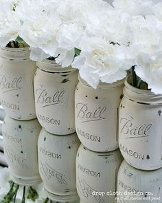 white flowers are in mason jars with the words chalk painted on them, and an image of