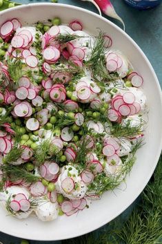 a white bowl filled with radishes and other vegetables on top of a table