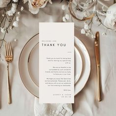 a place setting with white flowers and gold cutlery on the table for an elegant thank you card