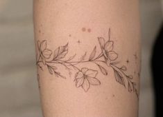 a tattoo on the leg of a woman with flowers and leaves drawn on it's side