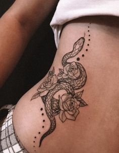 a woman's stomach with a snake and rose tattoo on the side of her belly