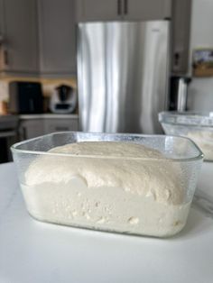 a cake in a plastic container sitting on a counter next to a silver refrigerator freezer